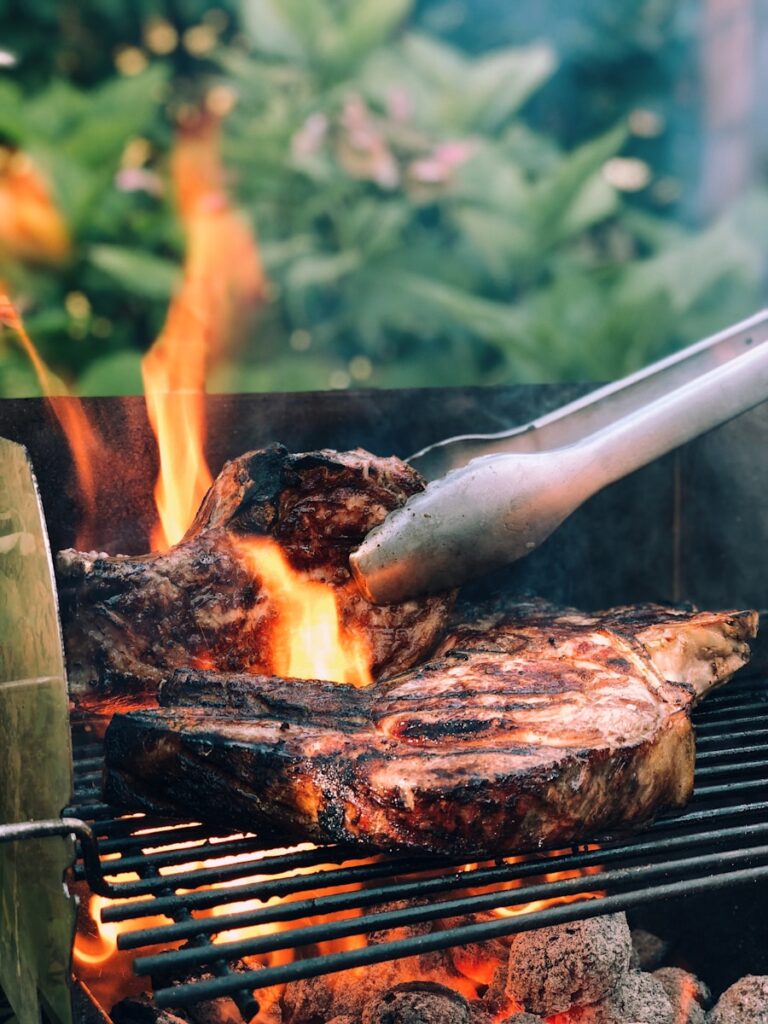 gray metal tong and grilled meat with fire garden barbecue